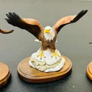 A detailed eagle figurine with outstretched wings on a wooden base.