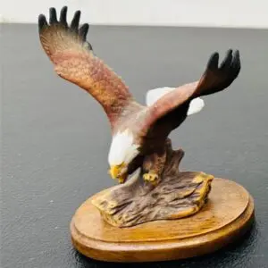 A detailed eagle sculpture with wings spread, perched on a wooden base.