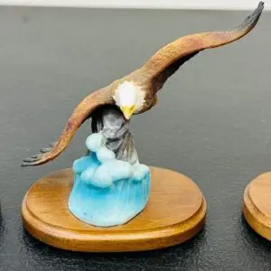 A bald eagle sculpture soaring over a woman in blue on a wooden base.