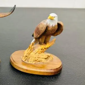 Wooden sculpture of a bald eagle perched on a branch.