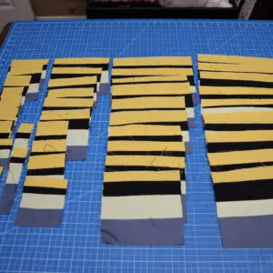 Stacks of yellow and black paper strips organized on a blue cutting mat.