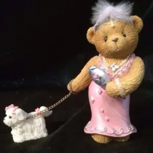 Teddy bear in a pink dress walking a small white dog.
