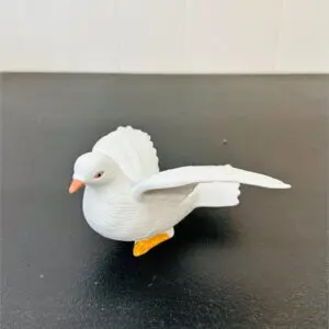 A white ceramic bird figurine with detailed wings and an orange beak.