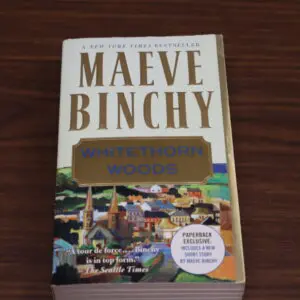 A paperback copy of Maeve Binchy's novel 'Evening Class' on a wooden surface.