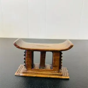 Small wooden stool with three legs and a curved top.