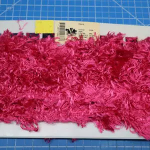 Bright pink textured fabric piece on a blue cutting mat.
