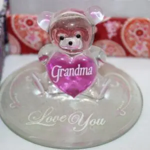 A teddy bear holding a heart with 'Grandma' on a glass base saying 'Love You'.