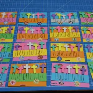 Colorful paper cutouts of crosses and people arranged on cards.