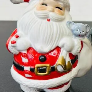 A festive Santa Claus figurine holding a small gray animal.