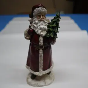Vintage Santa Claus figurine holding a Christmas tree.