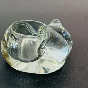 Clear glass cat-shaped paperweight on a dark surface.