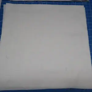 A plain white square cloth on a blue surface.