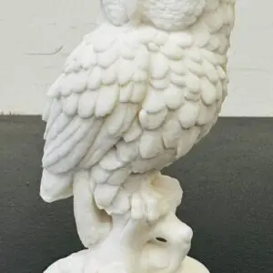 White owl sculpture perched on a branch with detailed feathers.