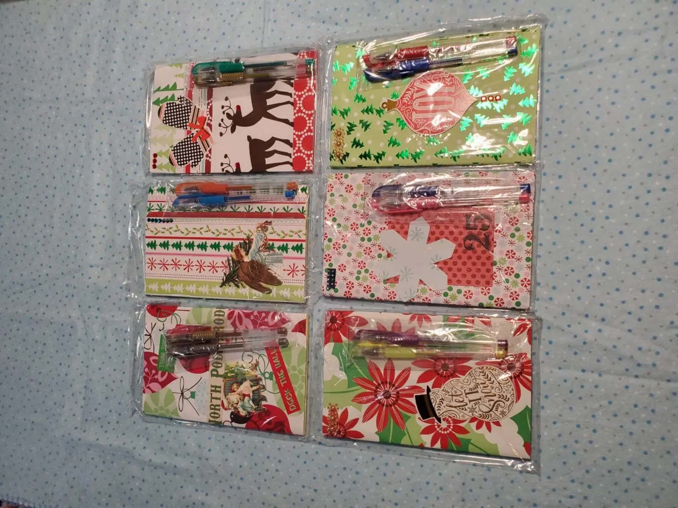 Colorful holiday-themed notebooks with matching pens.
