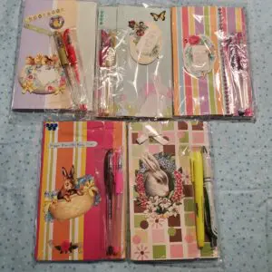 Colorful notebooks and pens arranged on blue fabric.