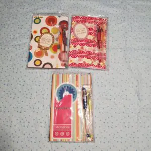 Colorful notebooks and pens arranged on fabric.