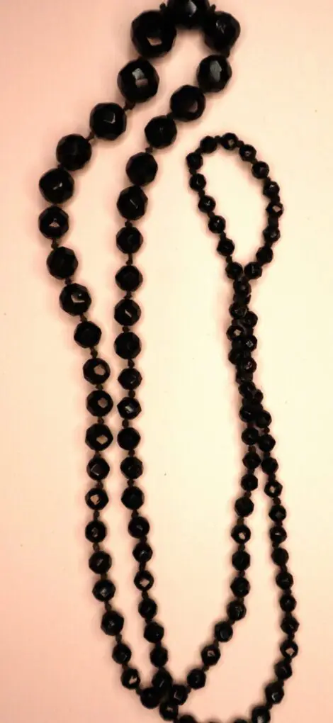 Black beaded necklace with varying shapes displayed.