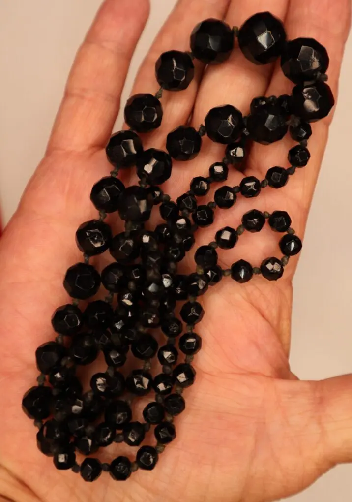 Black beaded necklace displayed on a hand.
