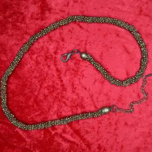 Bronze beaded necklace displayed on red fabric.