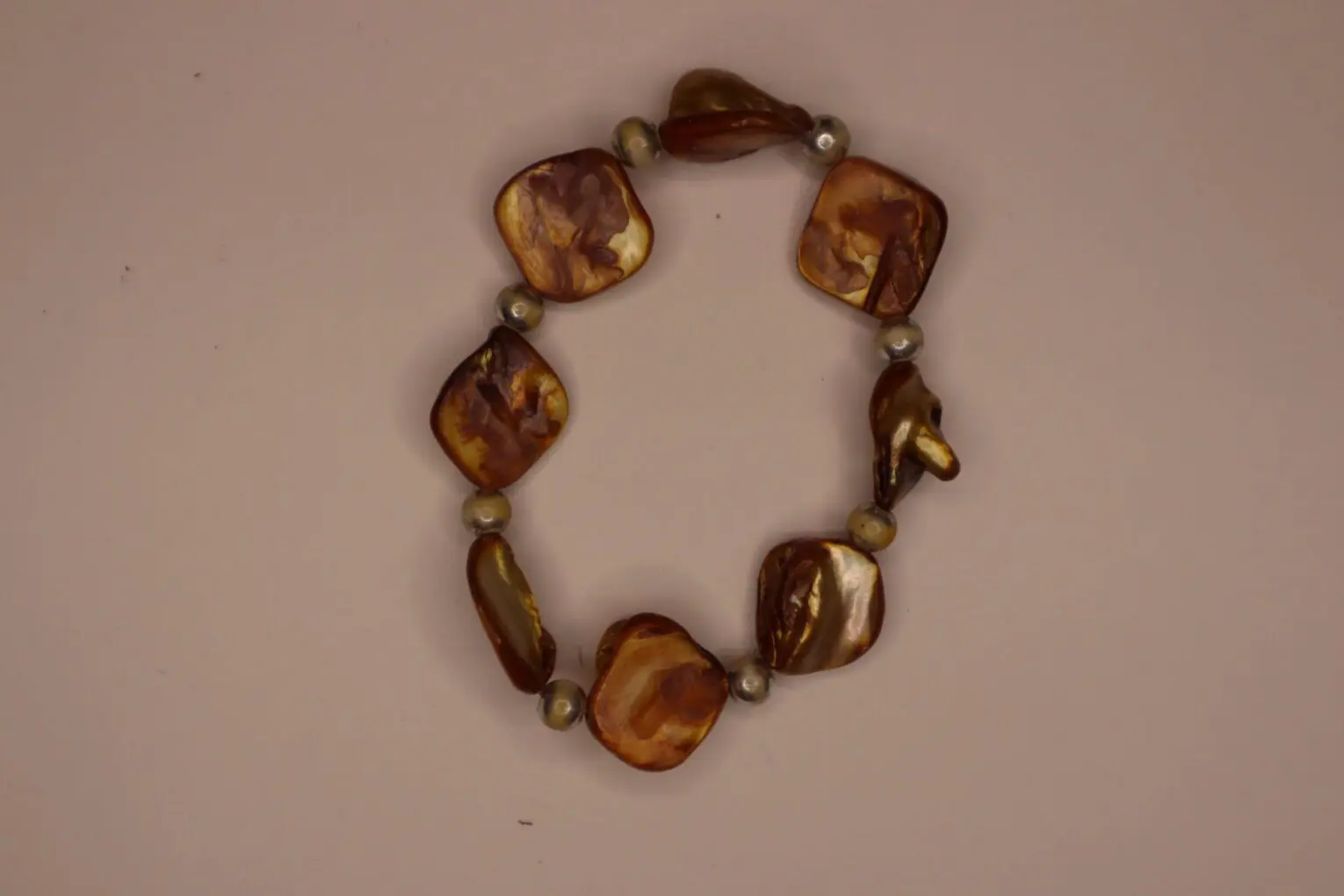 Brown beaded bracelet with unique shapes displayed.