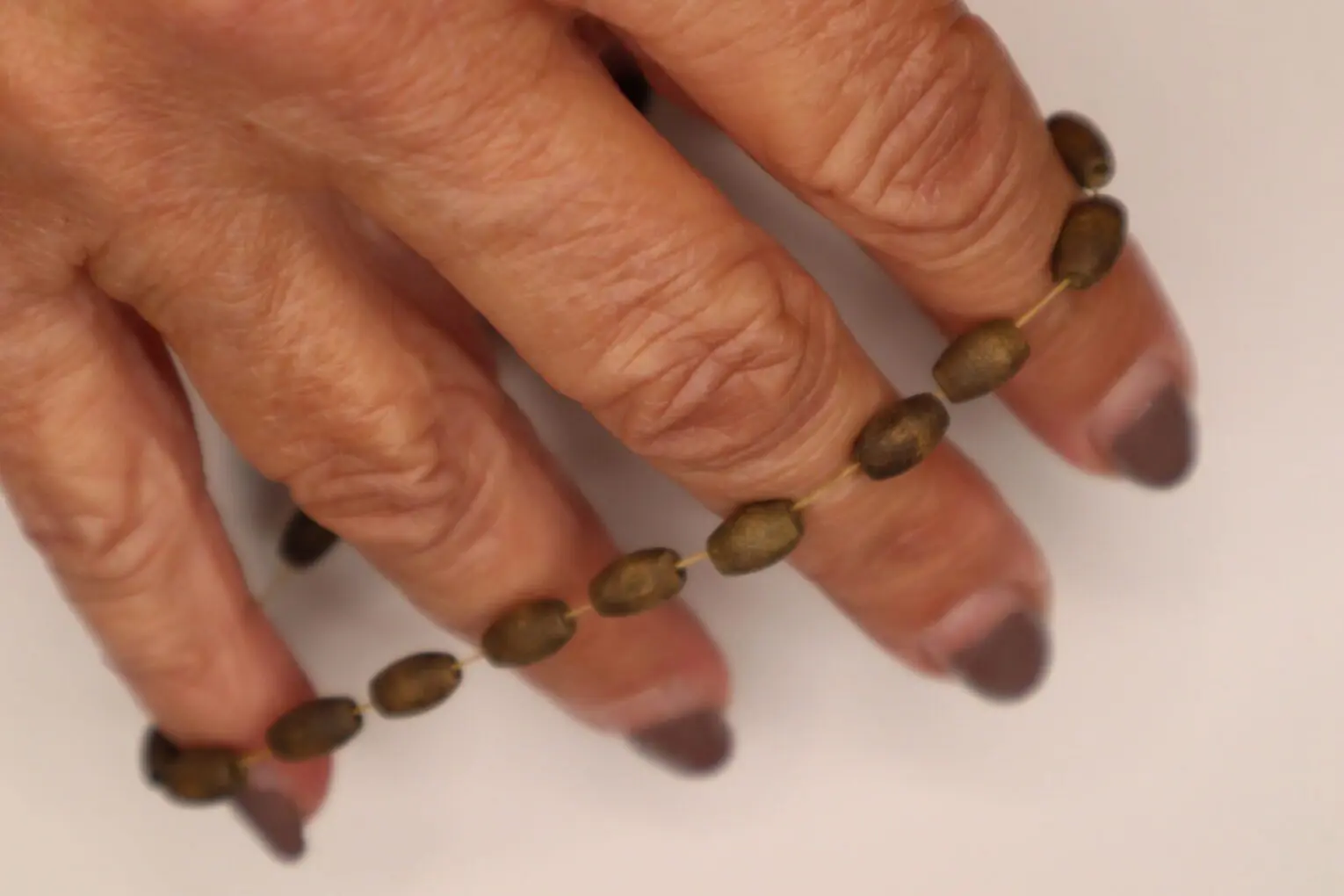 Brown beaded bracelet held between fingers.