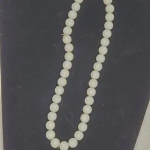 Elegant white bead necklace displayed on black.