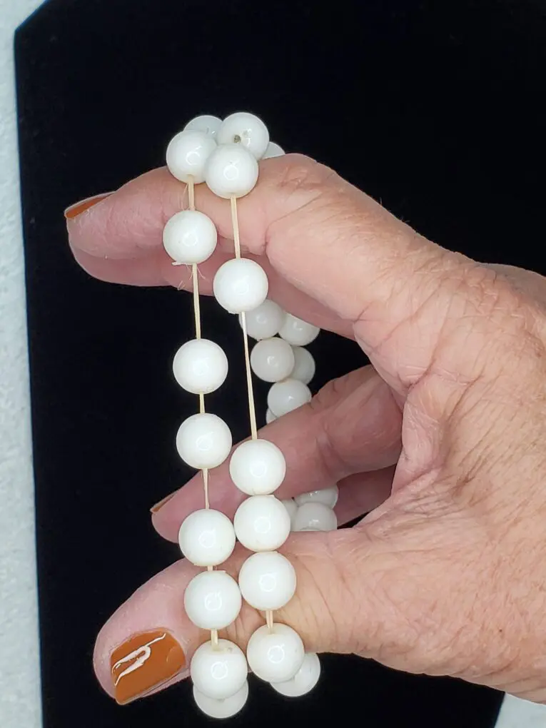 White beaded bracelet held in a hand.