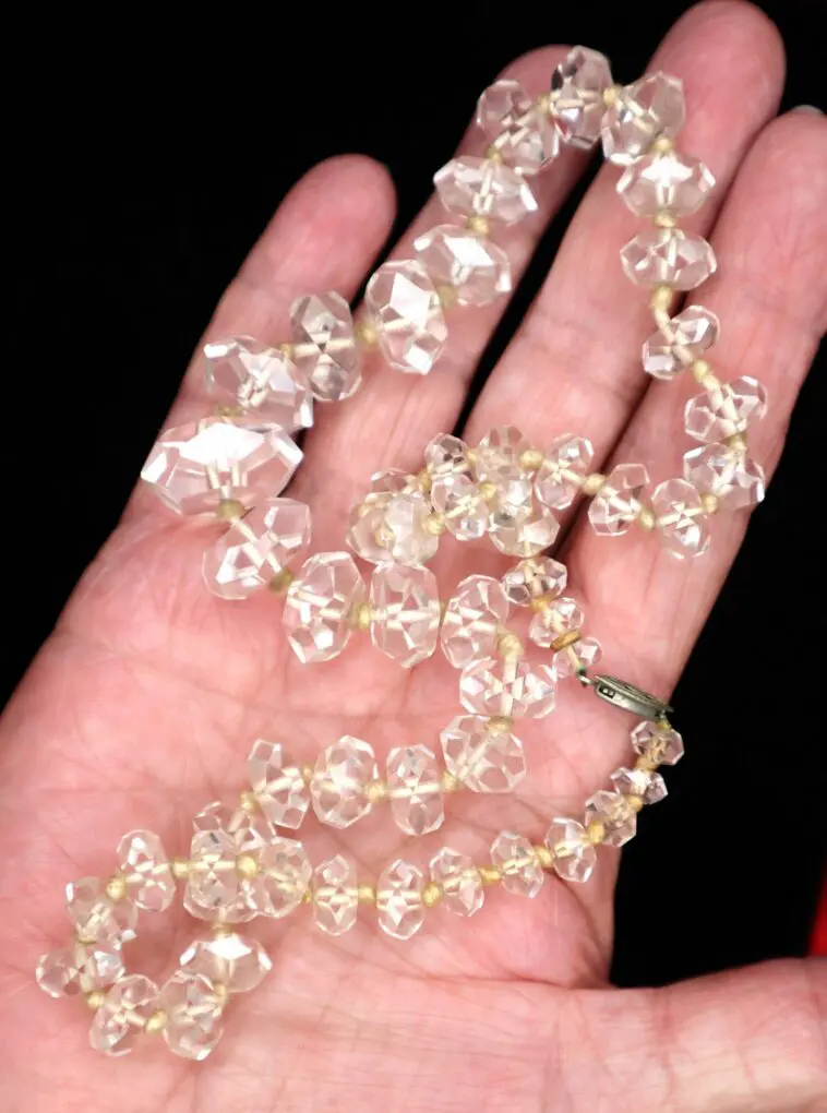 Clear beaded necklace displayed on a hand.