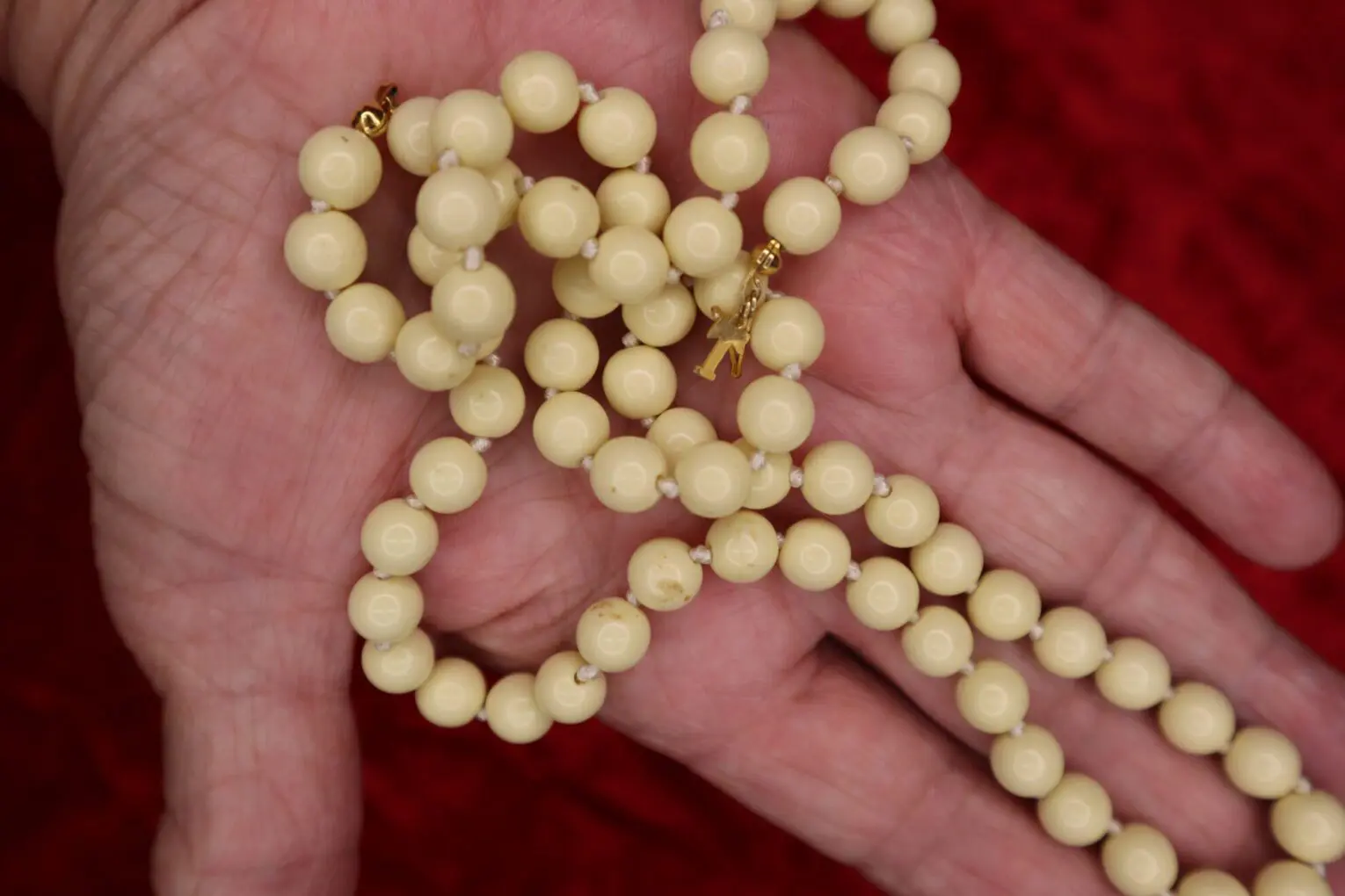 Cream-colored beaded necklace held in a hand.