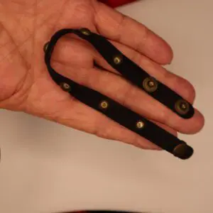 Black strap with decorative brass buttons held.