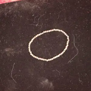 Delicate beaded bracelet arranged on dark fabric.