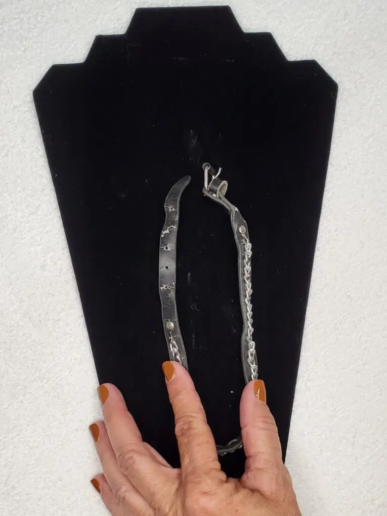 Silver bracelet displayed on a black stand.