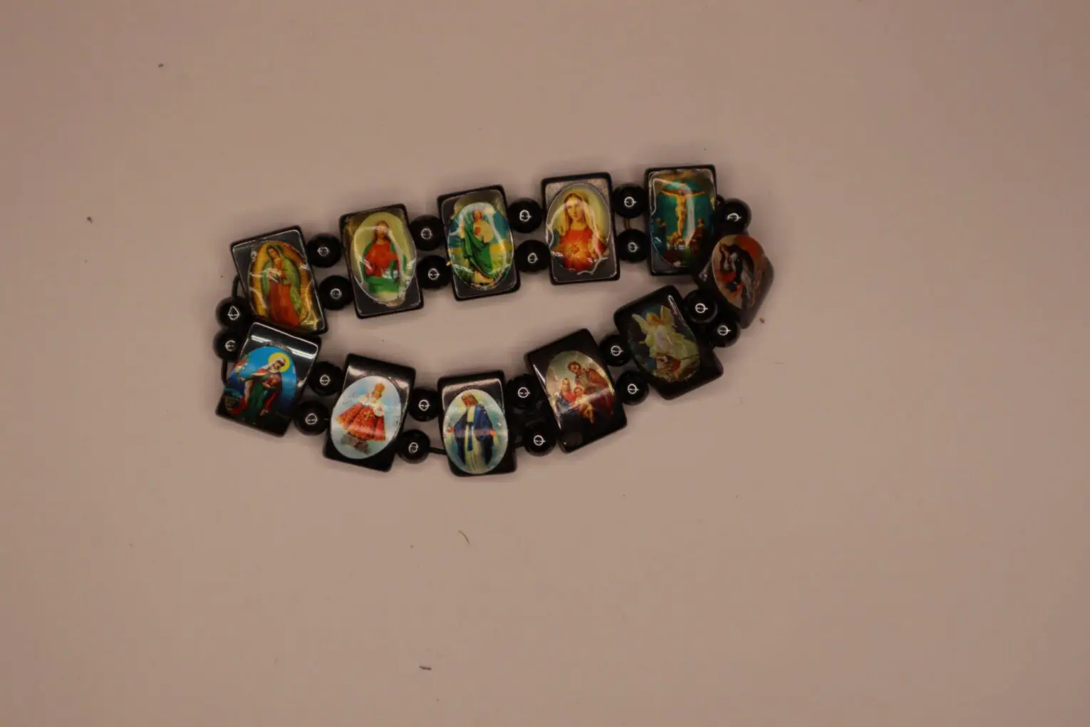 Bracelet featuring religious imagery on black links.