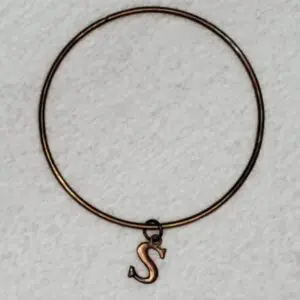 Bronze bracelet with a decorative 'S' charm.