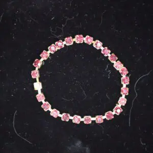 Pink beaded bracelet with gold accents displayed.