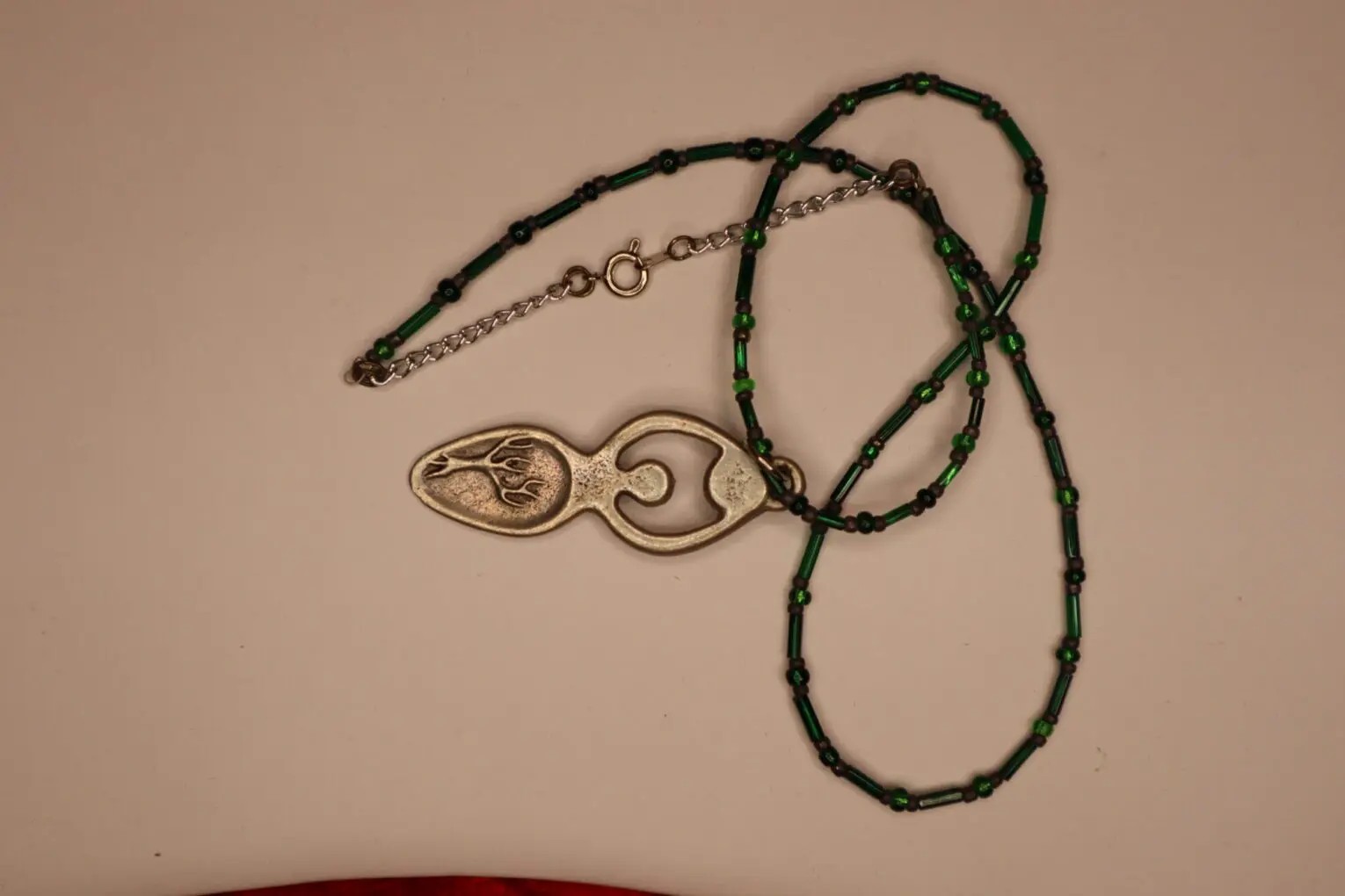 Beaded necklace with silver pendant and green accents.