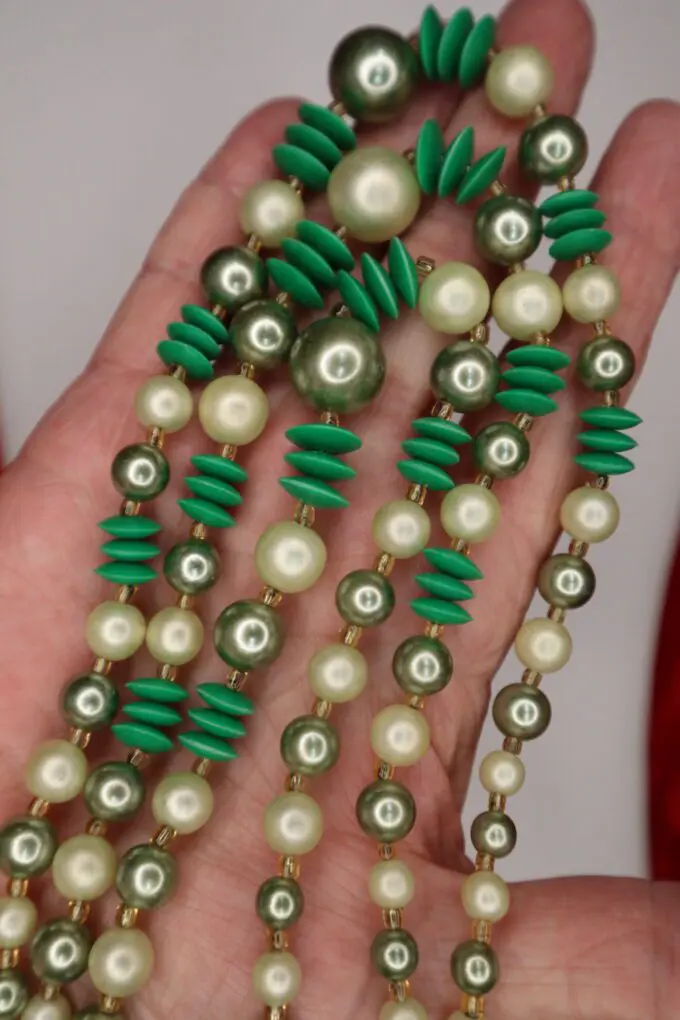 Green and cream beaded necklace held in hand.