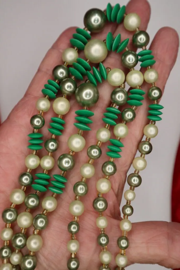Green and pearl beaded necklace held in hand.