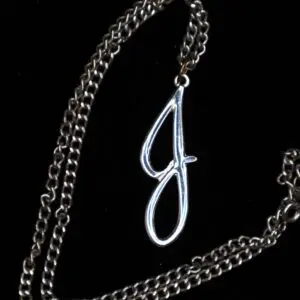 Silver necklace with a stylized letter pendant.