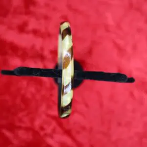Brown and cream patterned bangle on red background.