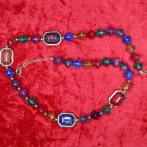 Colorful crystal necklace displayed on red fabric.