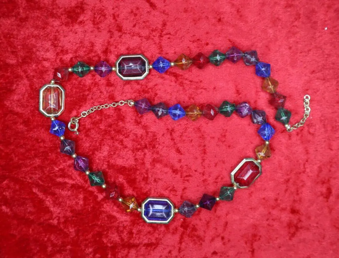 Colorful crystal necklace displayed on red fabric.