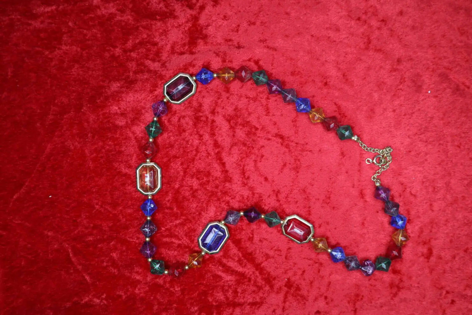 Colorful beaded necklace displayed on red fabric.