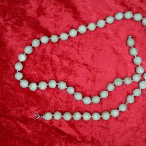 Light green beaded necklace on red background.