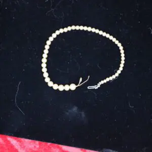 Cream-colored beaded necklace on dark background.