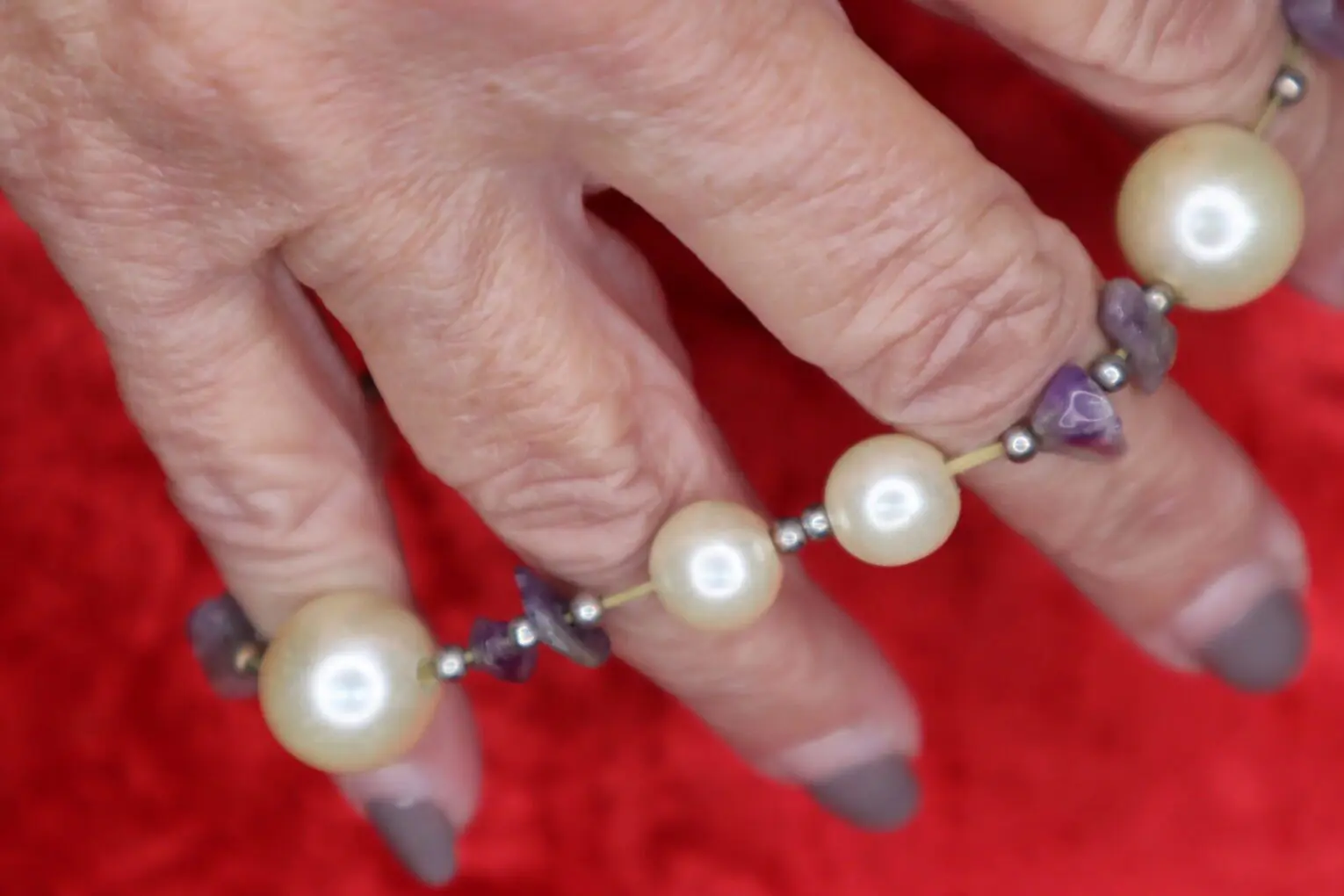 Pearl and amethyst beaded bracelet on hand.