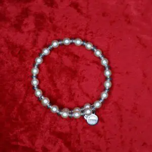 Silver pearl beaded necklace on red fabric.