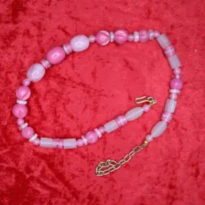 Pink beaded necklace displayed on red fabric.