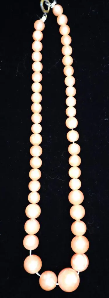 Peach-colored beaded necklace on black background.