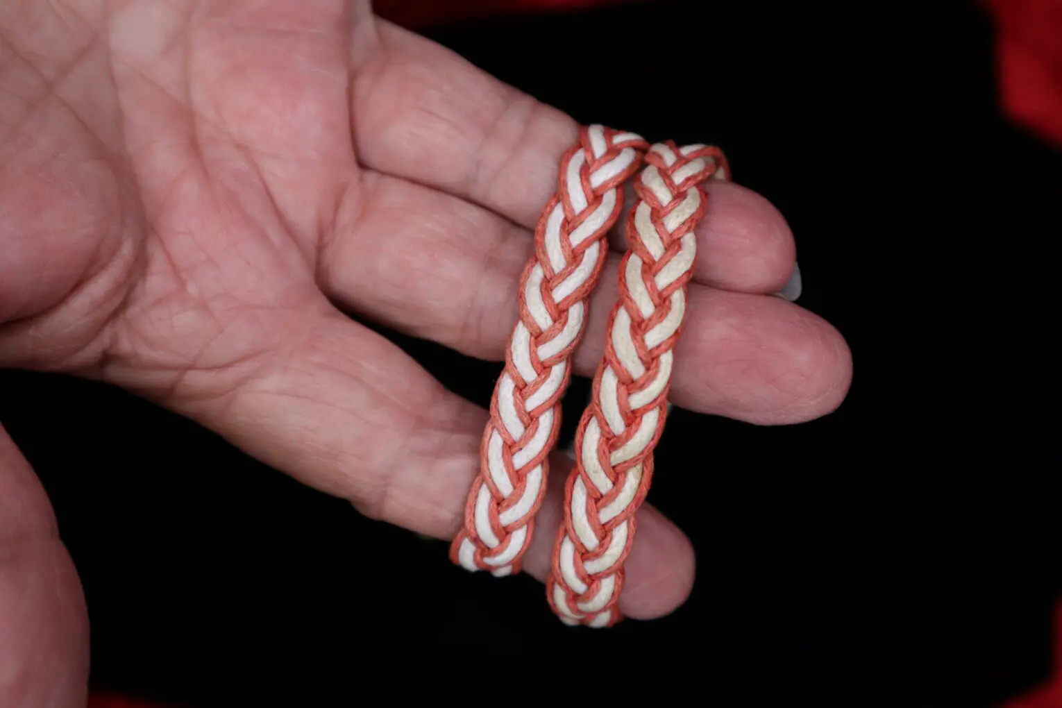 Braided bracelets in hand with orange accents.